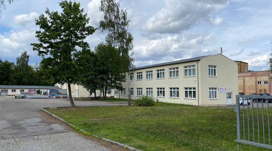 Gewerbestandort Borssenanger 10 mit Firmenlogos, Fahnen und Parkplatz.