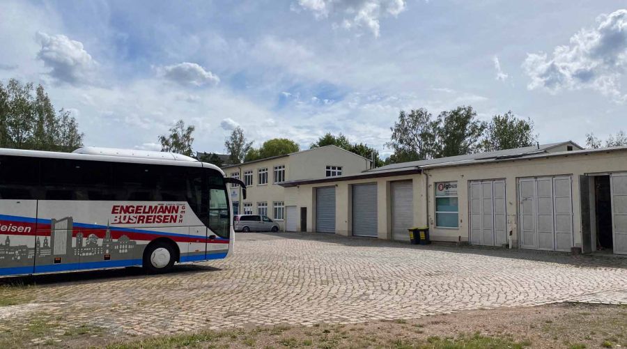 Werkstätten am Gewerbestandort Borssenanger mit Engelmann Busreisen Bus auf einem gepflasterten Hof.